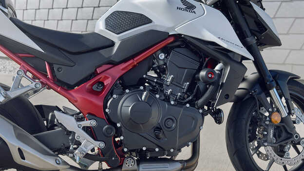 Honda CB750 Hornet con hombre apoyado en el edificio.