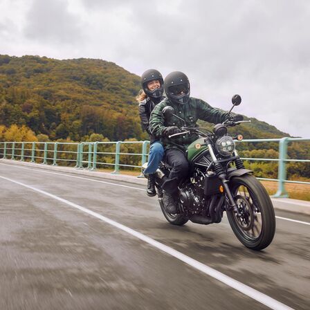 Honda CL500 on road with rider and pillion.