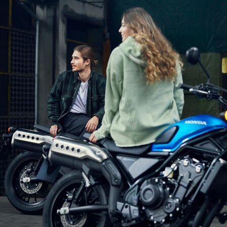 Honda CL500 con modelos sentados en la moto.