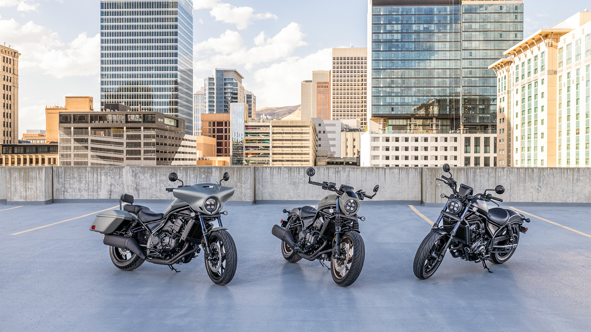 Tres motos CMX1100 en el exterior, delante de edificios modernos.