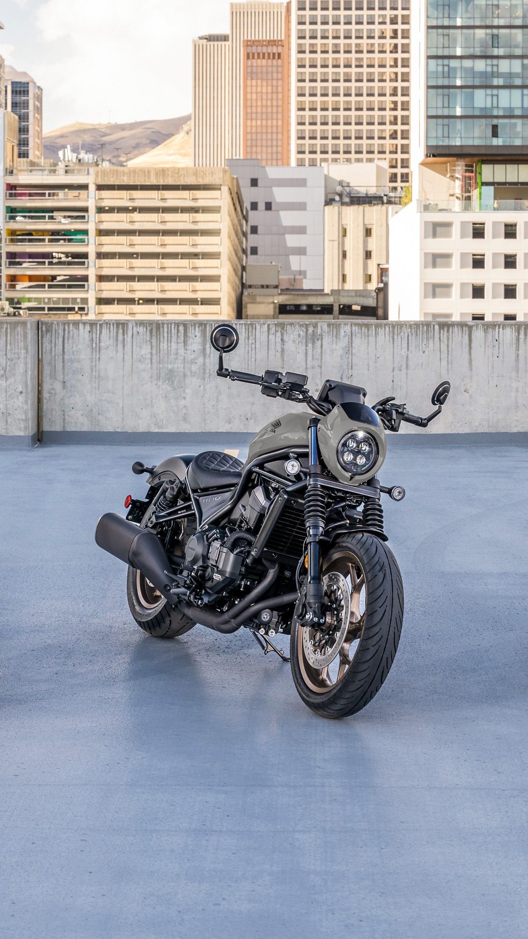 Una moto CMX1100 en el exterior, delante de un edificio moderno.