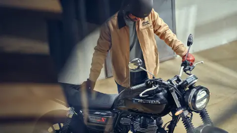 Toma frontal de ¾ de la GB350S con un piloto frente a una cafetería