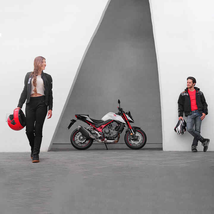 Hombre y mujer apoyados junto a la Honda CB750 Hornet.