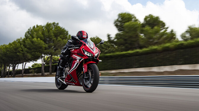 Vista de tres cuartos delantera de la Honda CBR650R en circuito con piloto