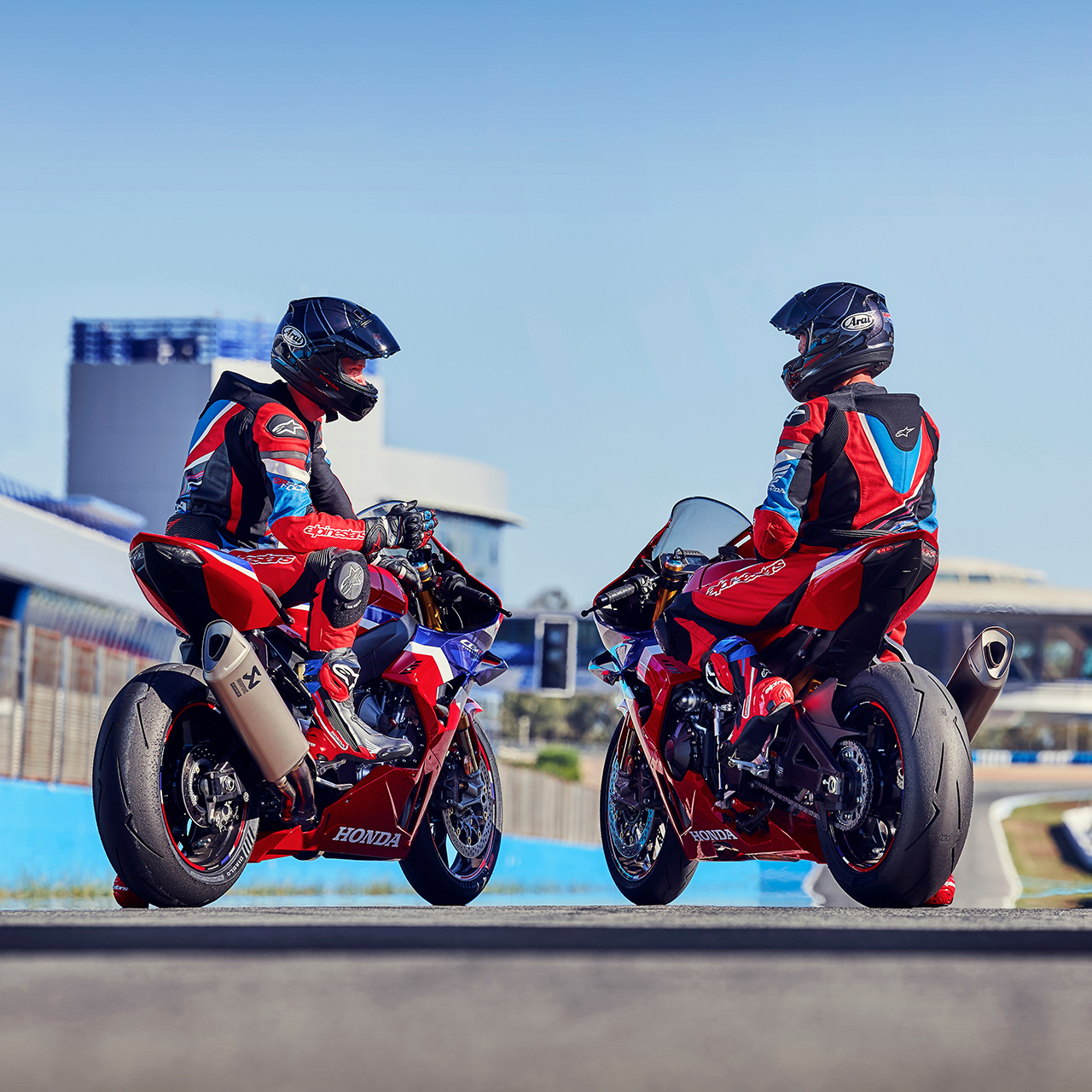 Dos motociclistas de espaldas con la Honda CBR1000rr-r Fireblade en una pista de carreras. 