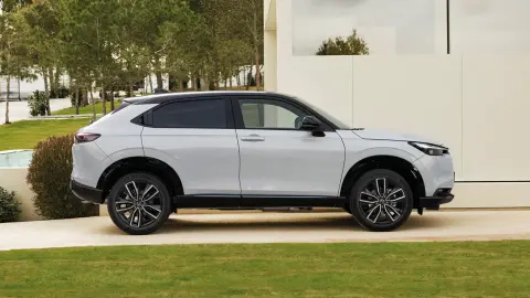 Vista lateral del Honda HR-V en el exterior de un hotel, con una pareja caminando. 