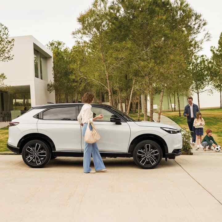 Pareja andando al lado de un HR-V estacionado en el exterior, junto a un edificio. 
