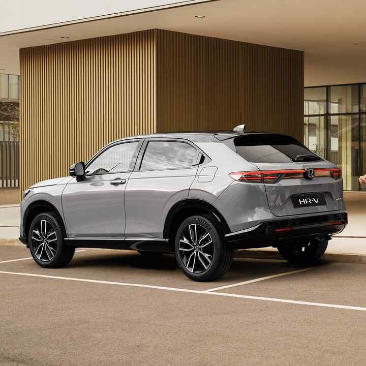 Mujer andando junto a un HR-V estacionado. 