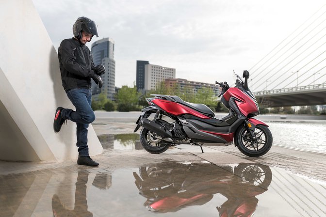 motorista con scooter honda forza roja