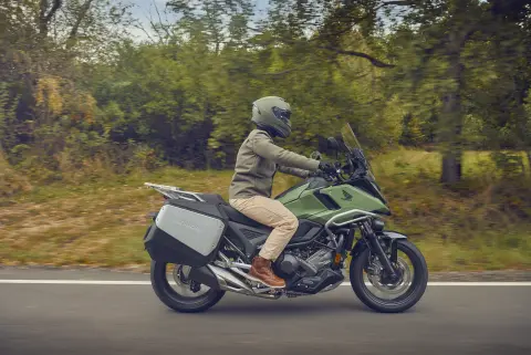 Toma lateral de una modelo conduciendo la motocicleta NC750X en una ubicación de la ciudad.