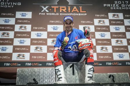 Toni Bou sentado en lo más alto del pódium mostrando orgulloso su medala de campeón